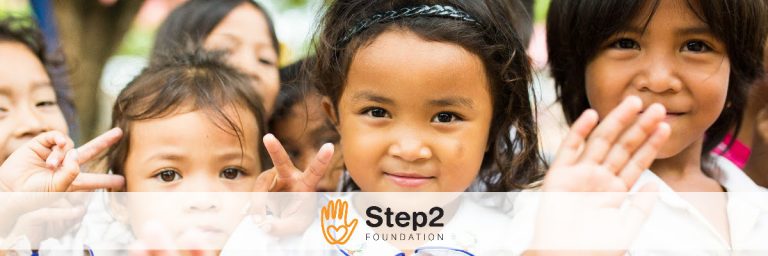 Young schoolchildren smiling and waving, shown alongside the Step 2 Foundation logo.