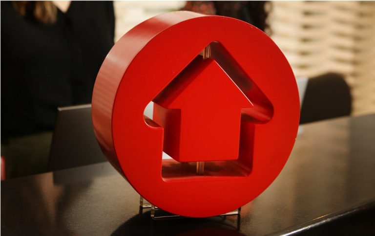 A small red house-shaped ornament sitting on a shelf.
